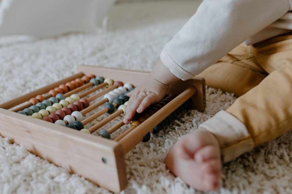 Toddler engaging with a wooden abacus on a fluffy carpet, promoting early learning.